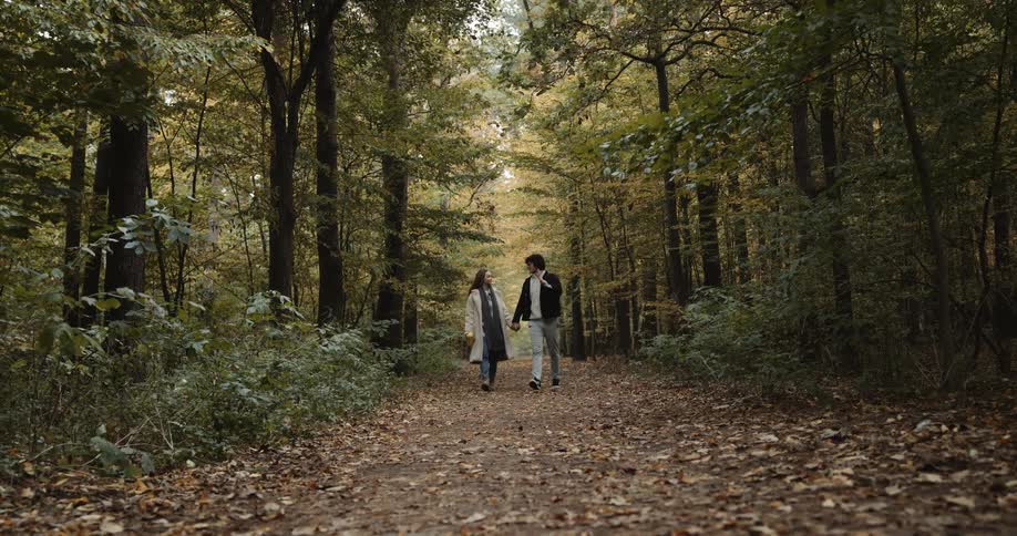 A couple are talking as they walk through the forest