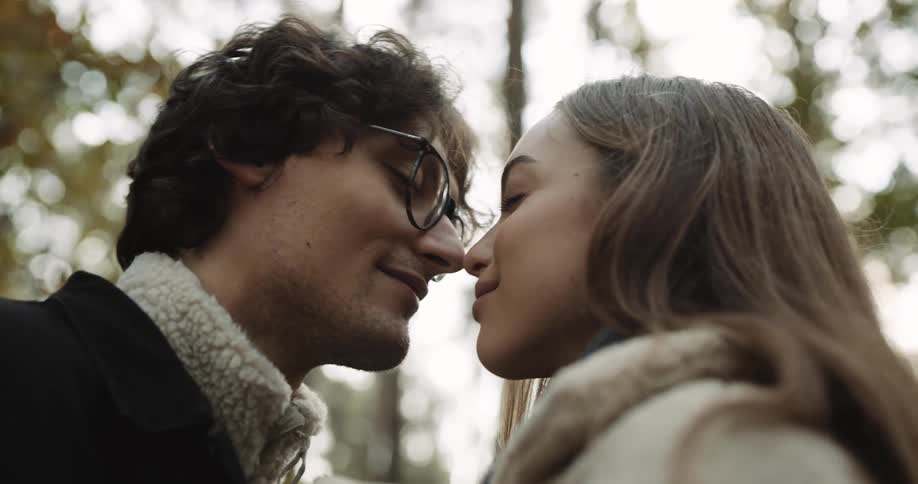 A couple standing in the woods rubbing noses