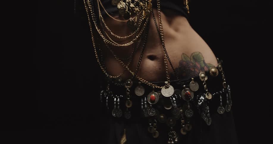 The mid section of a woman dancing with gold and silver jewelry all over