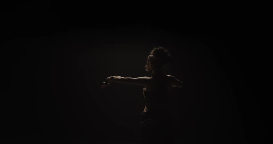A belly dancer dancing against a black background