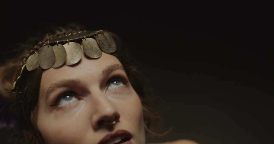 Belly dancer wearing headband and piercing with gold coins dances on stage