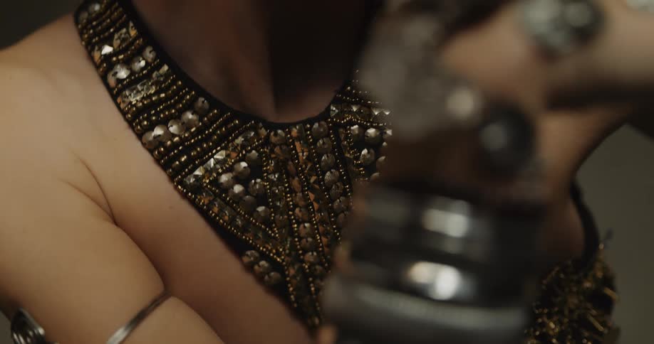 Belly dancer wearing bedlahheadbands with golden coins golden necklace and bracelets performs dance on stage