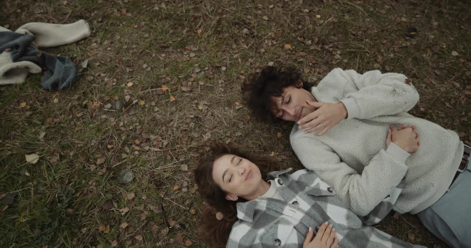 A young couple is laying down in the woods in the day time