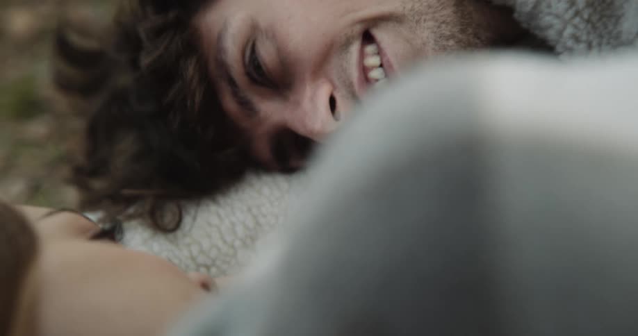Couple lie on ground together smiling as they talk