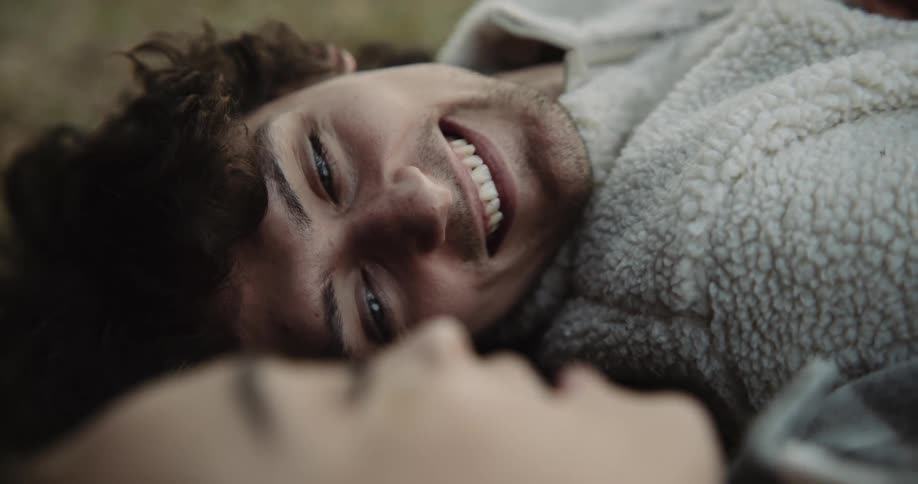 Man laying next to a woman feeding her a raspberry