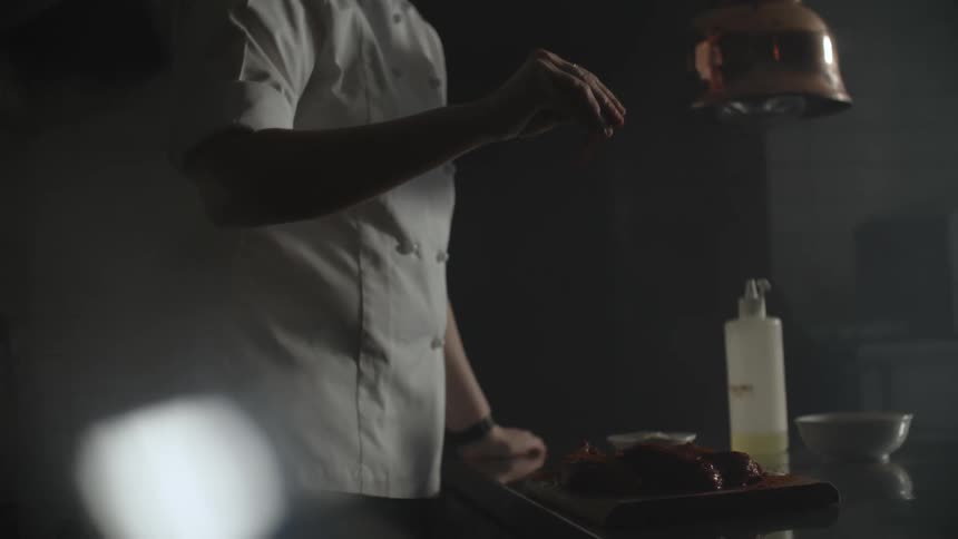 A chef sprinkles seasoning on food using his fingers