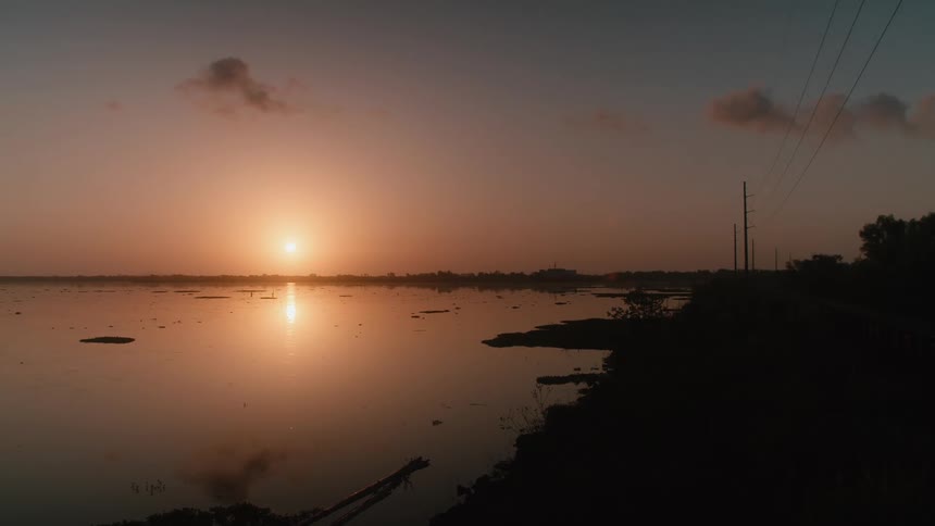 The sun shining over a calm lake at sunset