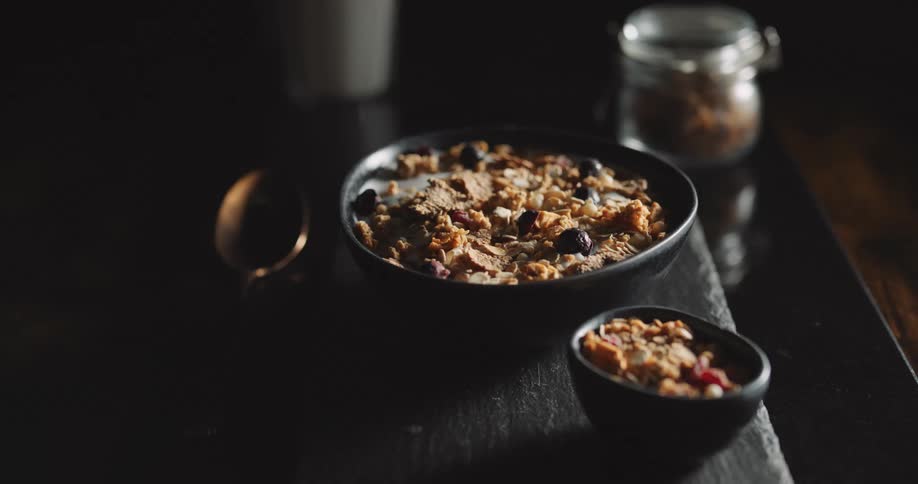 Two bowls of cereal are on the table next to a spoon