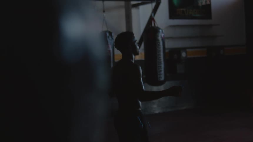 A man jumping rope while turning in a dark gym