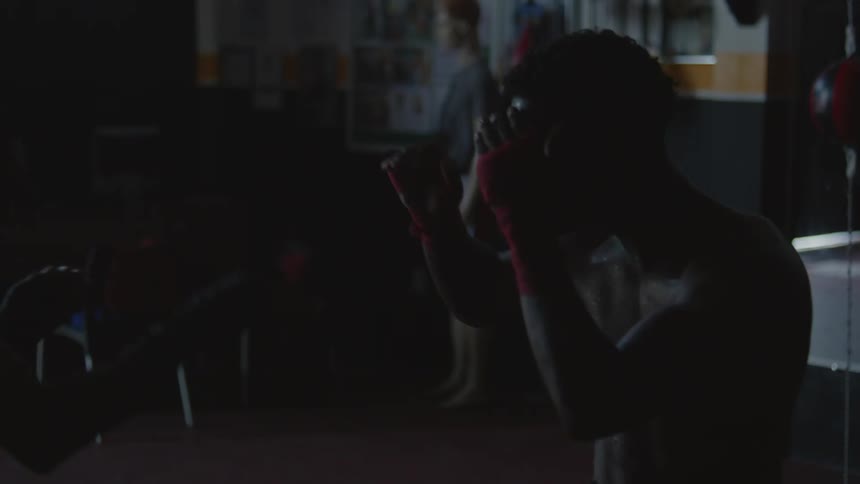 Two boxers wearing boxing trunks trains to fight in boxing gym