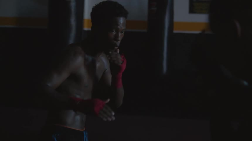 Two men are in a gym and boxing against each other