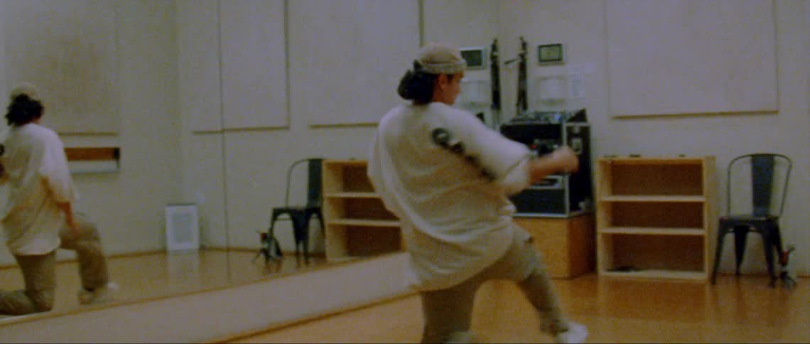 A man is dancing in front of a mirror in a room