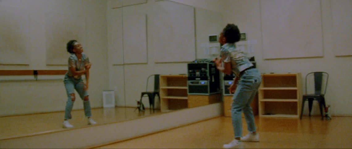 A woman is dancing by herself in front of a mirror