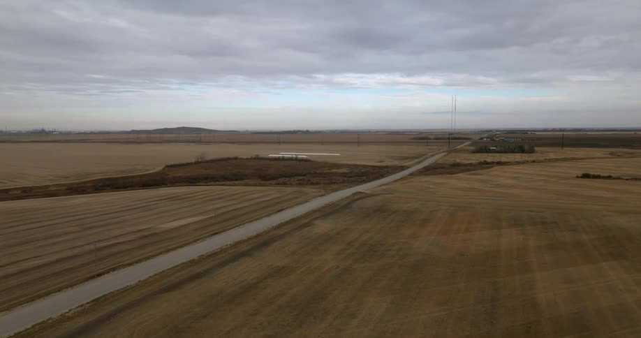 A narrow road runs through an empty field