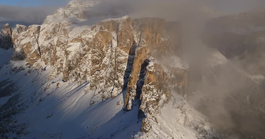 Snow covers mountain under thin low lying gray clouds