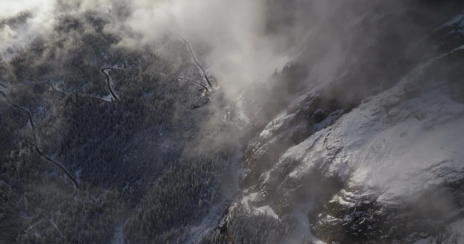 Snow covers mountain and forest while track moves through terrain