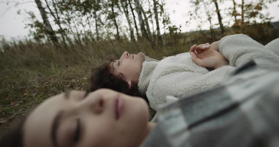 A young couple is laying down outside in the forest
