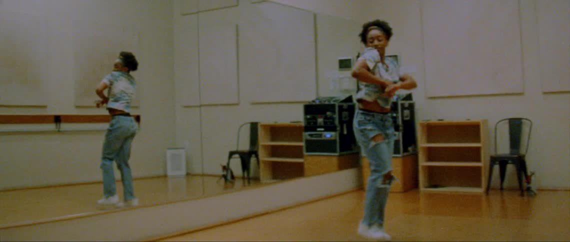 A woman is dancing in a room in front of a mirror