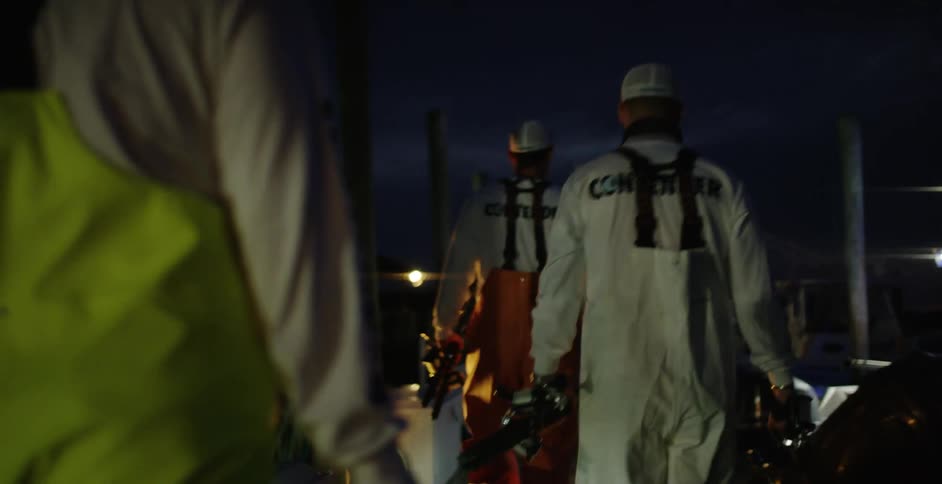Construction workers in suspenders walking outside at night