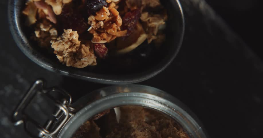A bowl and a jar of cereal granola nuts and berries