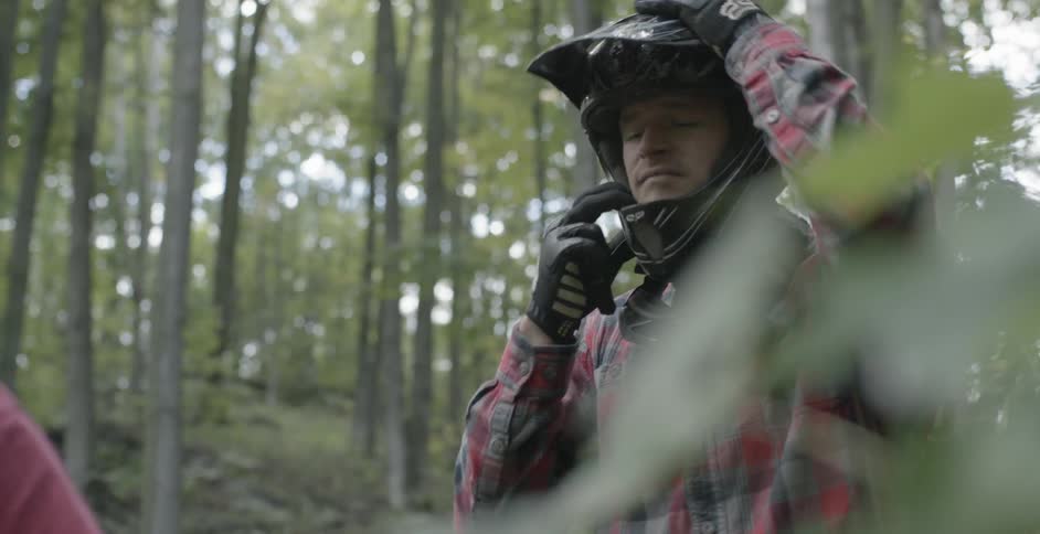 A man straps on his helmet in the forest