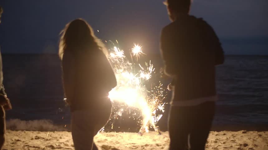 People watch fireworks on a beach