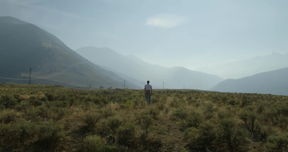 Woman with white t shirt and jeans walks on shrubland