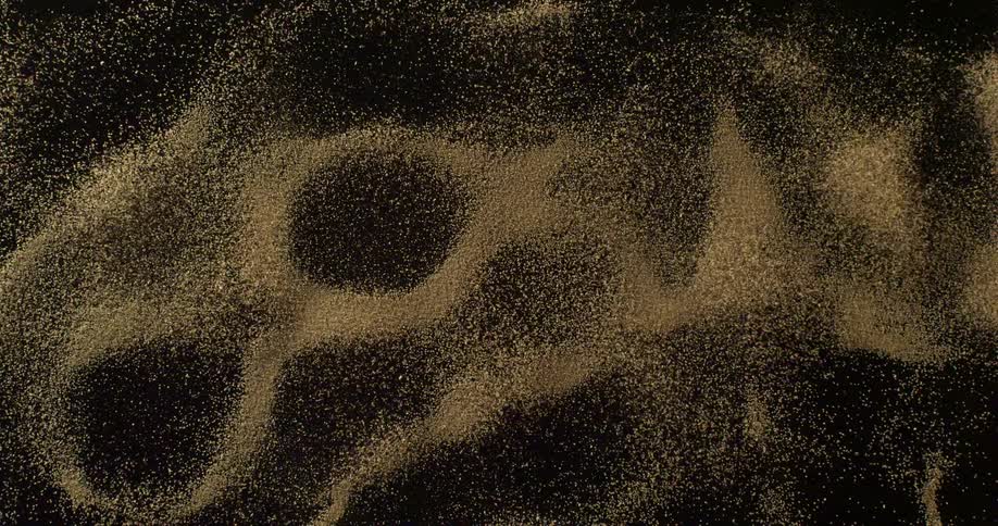 Close up of grains of sand forming patterns while vibrating over a metal sheet