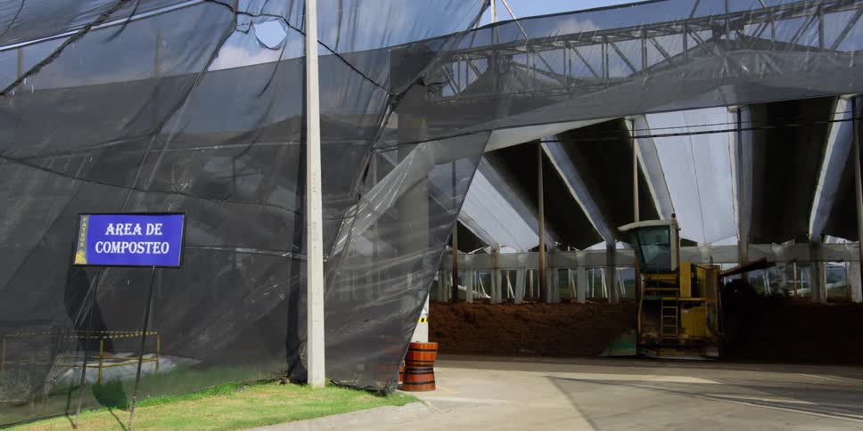 A person operates a tractor inside a composting tent