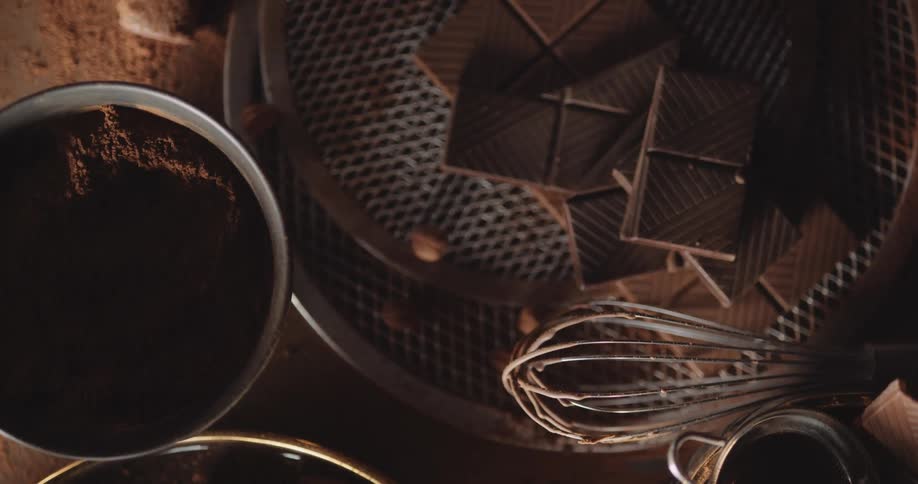 A whisk and kitchen tools with chocolate on a countertop