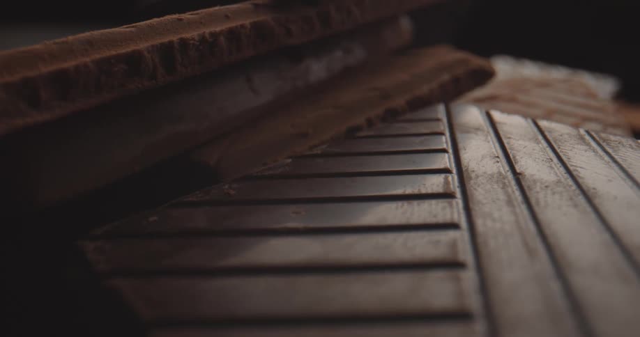 Stacked chocolate bars are scored with parallel lines and covered in cocoa powder