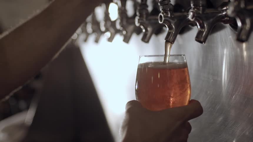 A bartender draws beer from a tap
