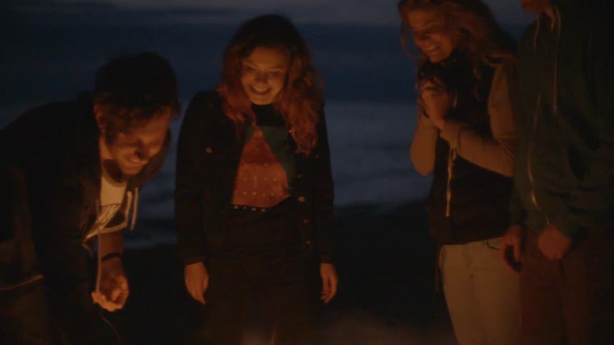 People stand around a fire at dawn talking