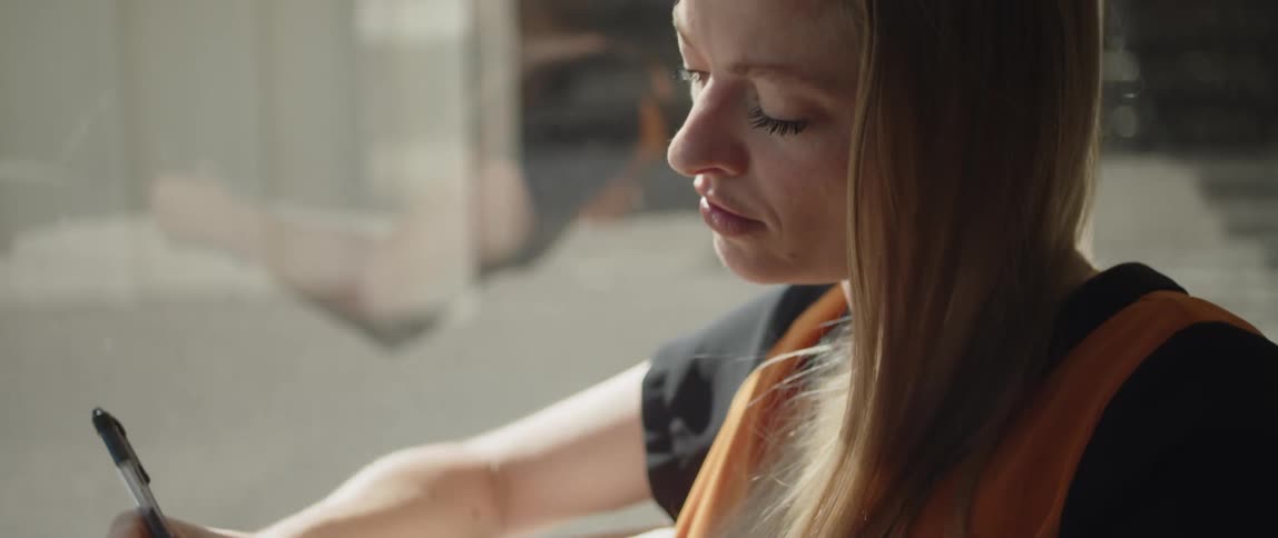 A woman sits on a couch writing in a notepad