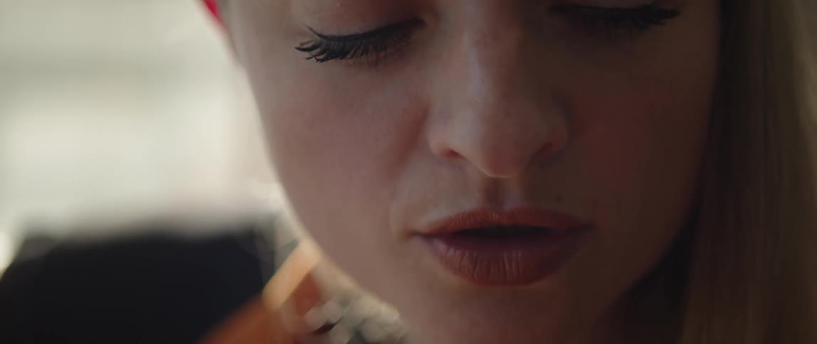 Close up of blonde womans face looking around and playing acoustic guitar