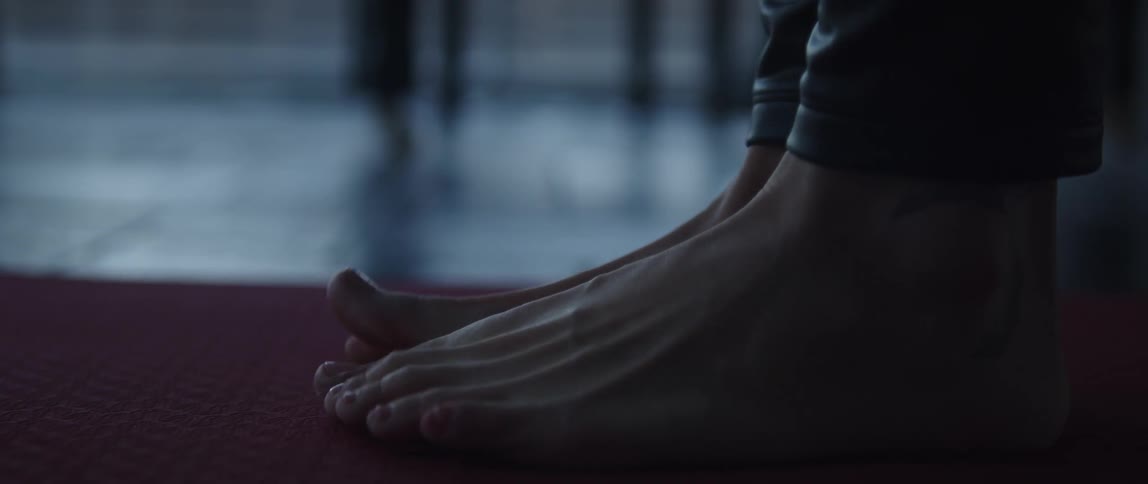 A barefoot woman standing on a yoga mat