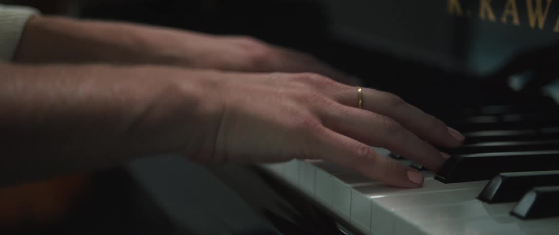 A woman with painted fingernails playing a piano