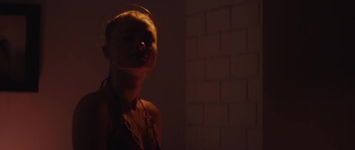 Silhouette of a woman standing in a room near a fire looking at the camera