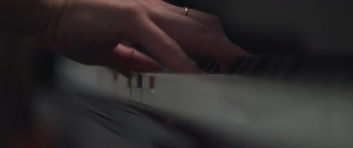 View of a womans hands as her fingers are pressing the keys of a piano as she plays