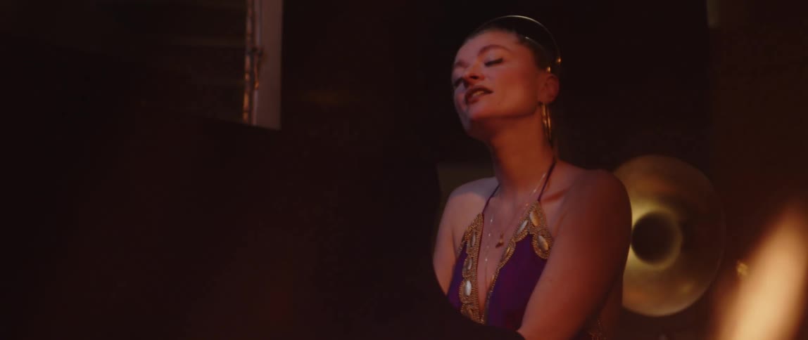 A young woman singing while playing a piano next to a burning fire