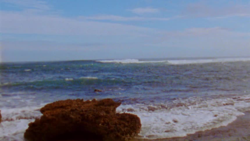 Ocean waves break against the beach on a sunny day