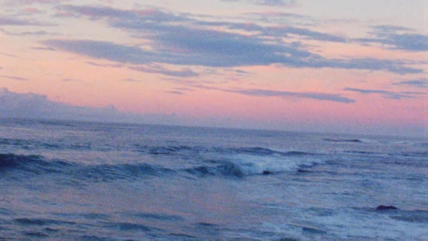 Landscape of ocean waves breaking agains the beach at sunset