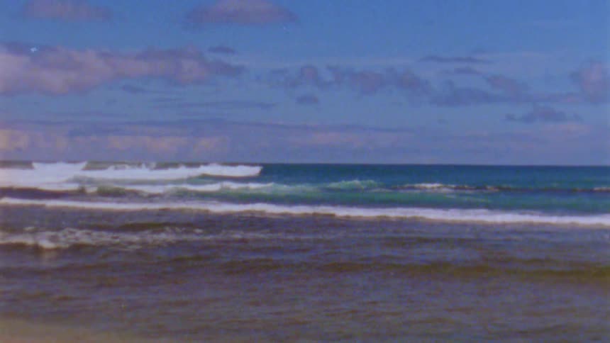 A sandy beach with ocean waves in the daytime