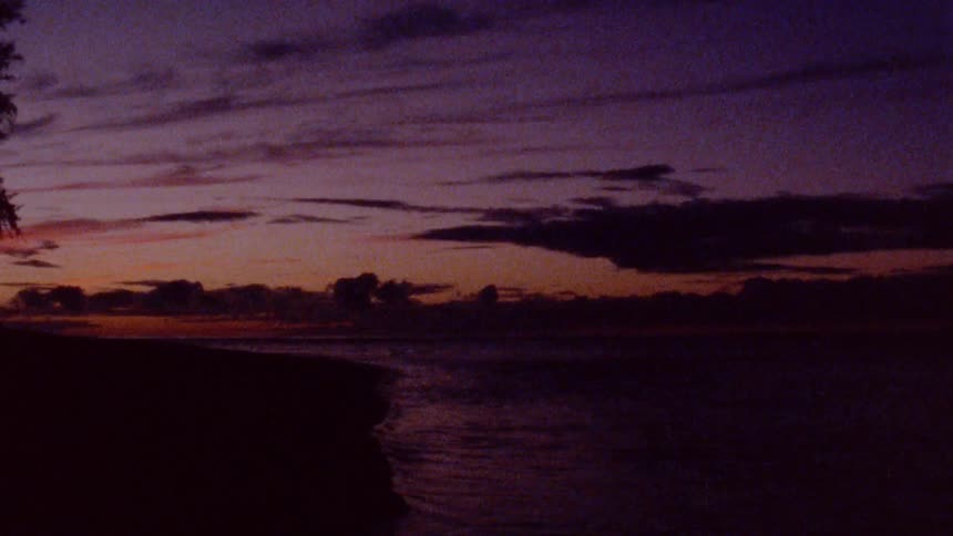 An unlit coastline at sunset