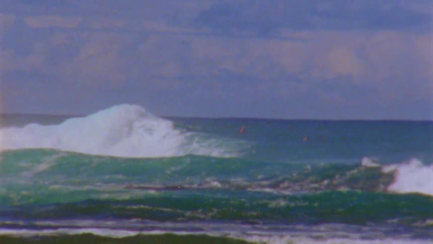 Far away people swim in wavy sea seen from the coast