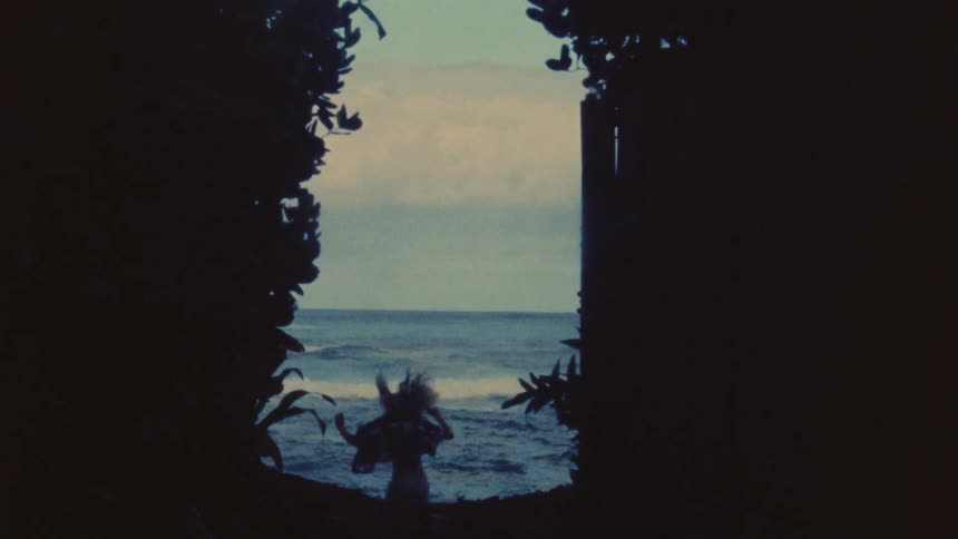 Woman with shirt and shorts runs through forest to the beach