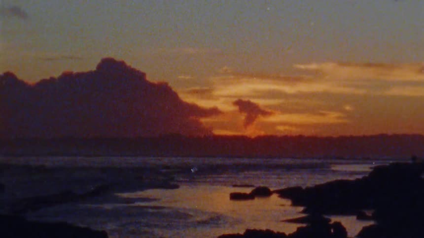 Ocean waves break against the shore at sunset