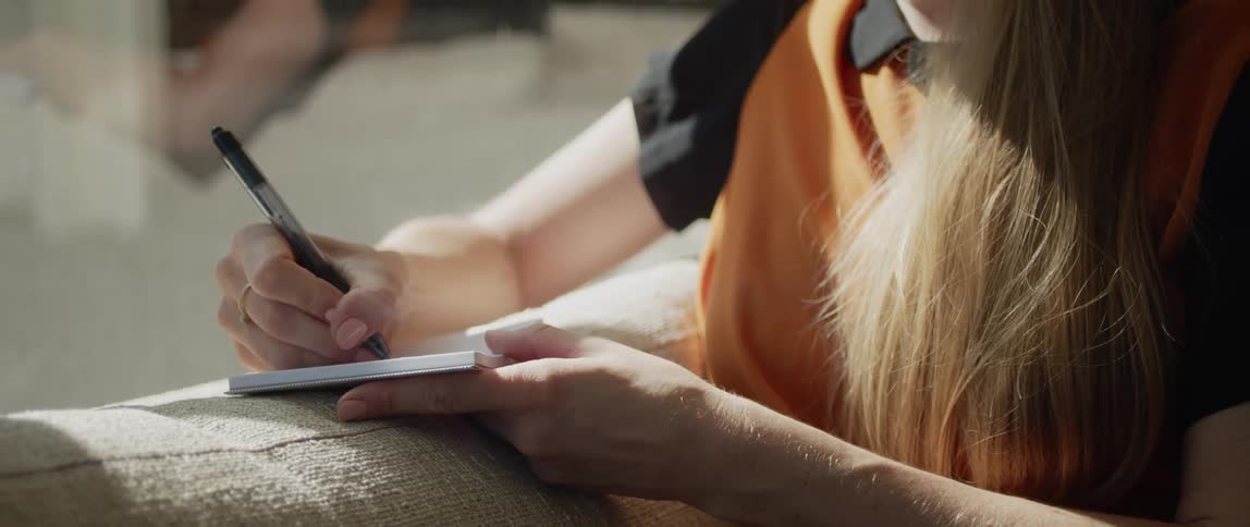 A woman is writing on her pad with a pen