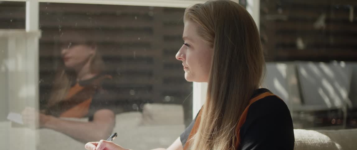 Blonde woman in black and orange shirt composes a song in the living room