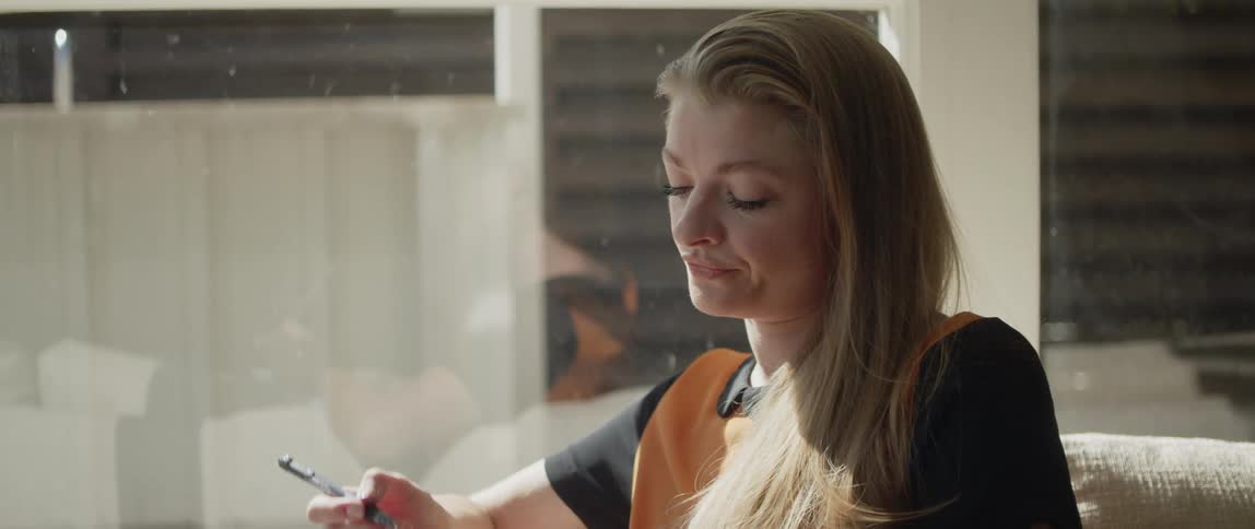 Young relaxed woman sitting on a couch at home writes on a notepad